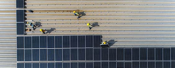 Montörer monterera ett stort antal solceller på en byggnads tak.