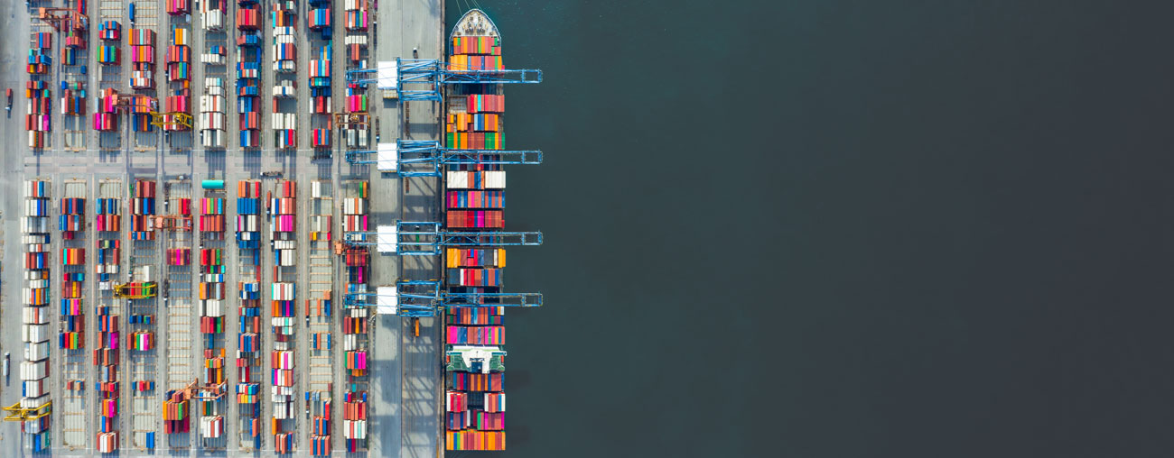 Lastfartyg och lastkaj fyllda med färgglada containrar, taget från ovan.
