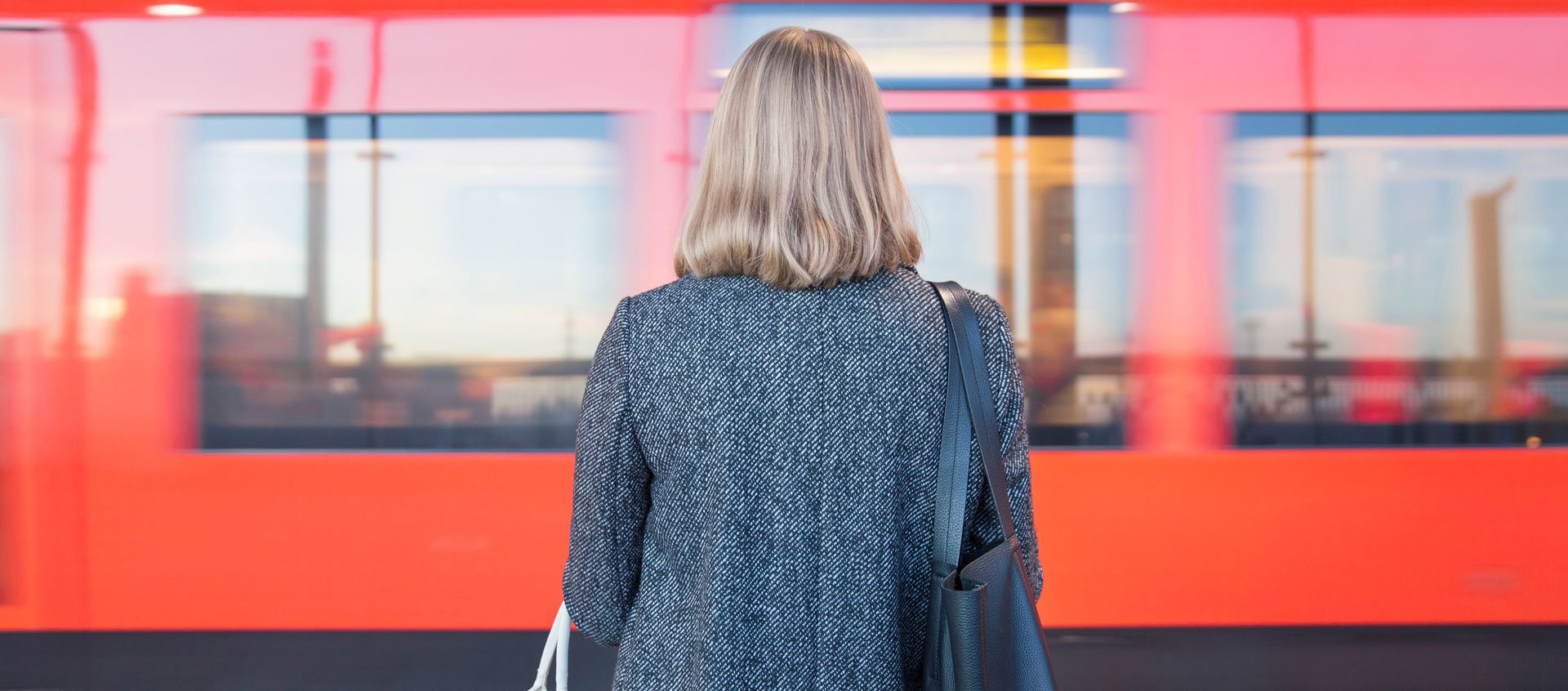 Kvinna som står på Helsingfors tågstation, fotograferad bakifrån.
