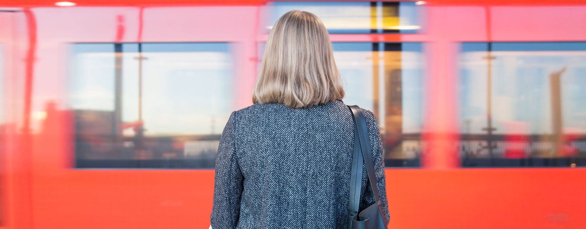 Kvinna som står på Helsingfors tågstation, fotograferad bakifrån.