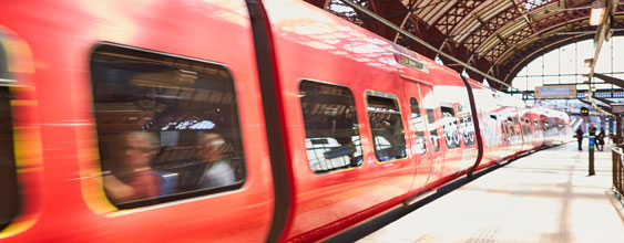 Rött tåg som rullar in på en tågperrong.